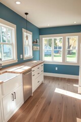 Sunlit teal kitchen with white cabinets and hardwood floors