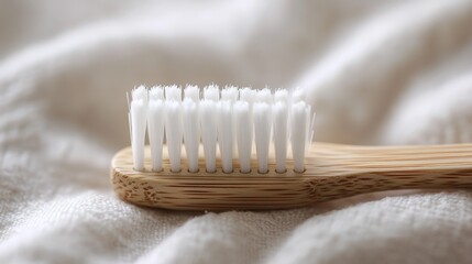 A close-up scene of a wooden toothbrush with white bristles, placed on a soft beige towel, blurred beige wall in the background