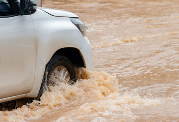 Different types of cars are driving through flooded roads caused by heavy rain. Ideas for car insurance and careful driving during flooded roads.