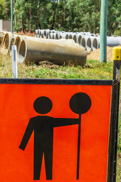 Large cement pipes laid out in rows behind a traffic sign