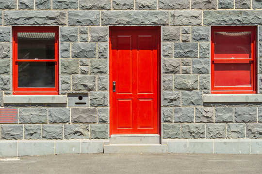 Red windows and doors in the facade of an historic blue stone building