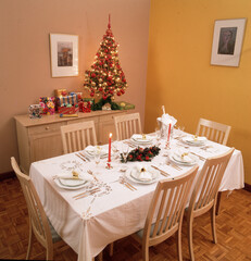 mesa de navidad con mantel velas  arboles de navidad con regalos casa living,sin gente 24 de diciembre 