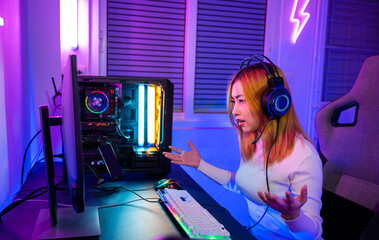 Game over you lose. Angry Asian gamer wearing gaming headphones playing joystick console video game on computer PC neon light at home feeling sad disappointed about game losing, player unhappy E-Sport © sorapop