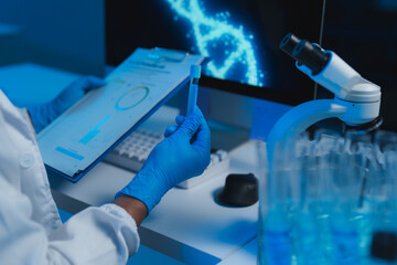 Scientist analyzing sample in laboratory with dna double helix on computer screen
