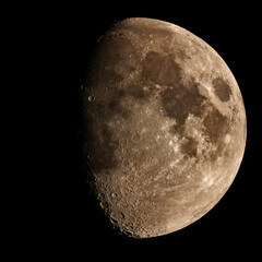 Detailed golden gibbous moon revealing craters against dark sky