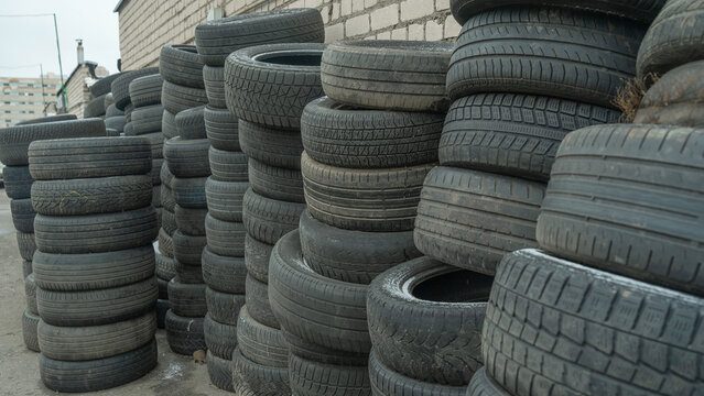 Storage of discarded old car tires outdoors, showcasing a pile of used tires ready for recycling. Highlighting environmental concerns and rubber waste management