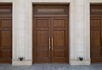 Three wooden doors with golden handles in front of a stone building