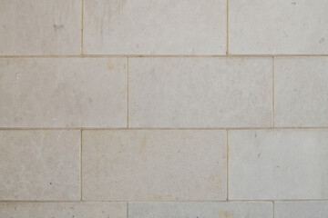 Close-up of a wall made of rectangular stone bricks in a neutral color