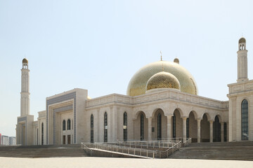 A beautiful central city mosque in Almaty, Kazakhstan, with a golden dome and tall minarets under a...