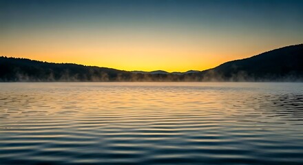 Obraz premium A serene lake at sunrise with mist rising from the water and distant mountains in the background.