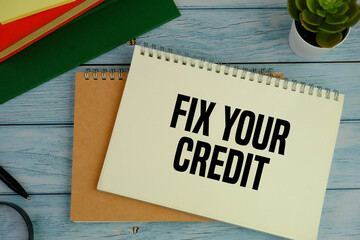 Top view of Fix Your Credit text message with calculator, alarm clock and magnifying glass on blue...