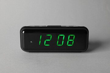 Digital alarm clock showing 12:08 o'clock on grey background