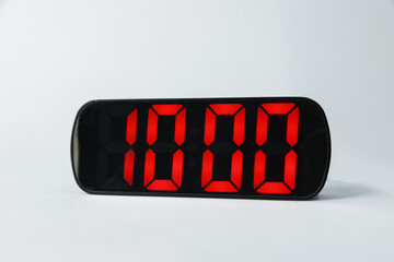 Digital alarm clock showing 10:00 o'clock on grey background