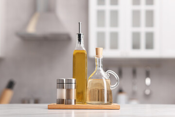 Bottles of salad dressings, salt and pepper on white table in kitchen