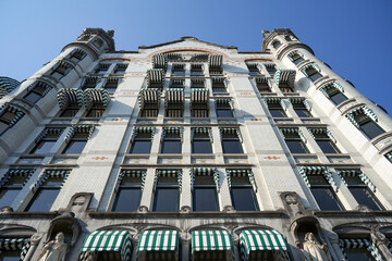 The facade of a historic building in Rotterdam with intricate architectural details, view from a low angle against a clear blue sky.