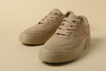 Stylish sneakers on beige background, closeup. Sportive shoes