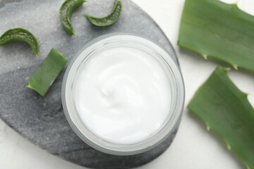 Cream and aloe leaves on white textured background, flat lay