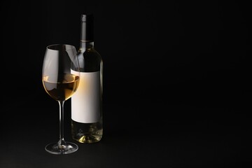 Tasty wine in glass and bottle on black background, space for text