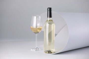 Bottle and glass of tasty wine on white background