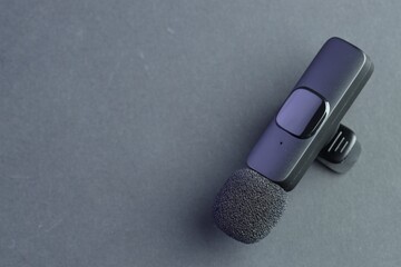 Lavalier microphone on grey background, top view. Space for text