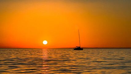 Scenic sunset over Melbourne’s harbor with colorful skies and boat silhouettes. A breathtaking seascape with vibrant orange and yellow hues reflecting on the water, creating a peaceful atmosphere