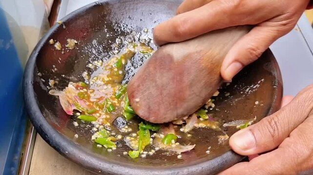 Street vendor skillfully prepare a sweet and spicy soy-based sauce made from palm sugar, shallots, garlic, chili, tamarind, and sweet soy sauce for Tahu Gejrot, Indonesian traditional cuisine 