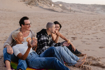 Friends eating donuts at the beach during sunset