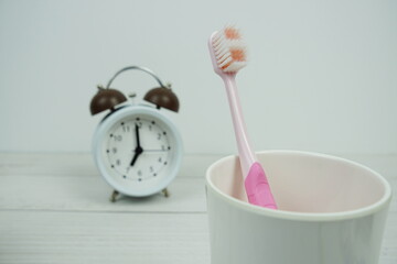 Toothbrush with alarm clock dental hygiene concept on wooden background