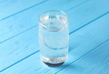 Refreshing soda water in glass on light blue wooden table, closeup
