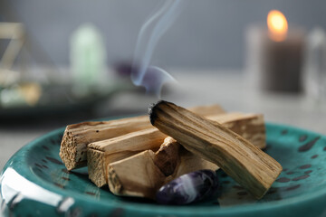 Smoldering palo santo stick and gemstone on table, closeup