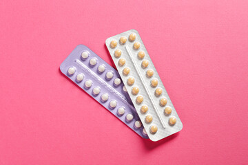 Blisters of contraceptive pills on pink background, top view