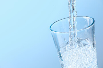 Pouring soda water into glass on light background, closeup. Space for text