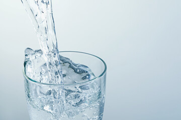 Pouring refreshing soda water into glass on light background, closeup. Space for text