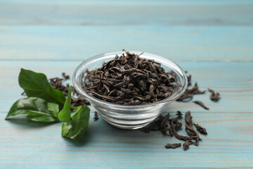 Dried and fresh tea leaves on blue wooden table, closeup
