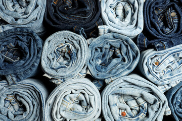 Different stylish rolled jeans as background, top view