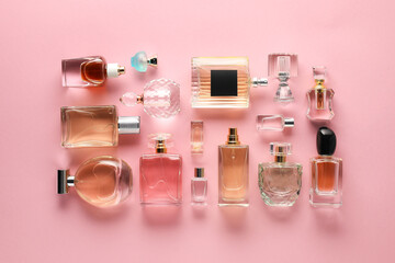 Bottles of various perfumes on pink background, flat lay