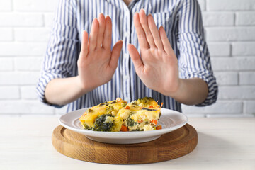 Woman refusing to eat piece of casserole at table, closeup
