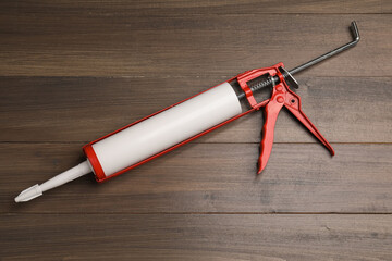 One glue gun on wooden background, top view. Construction tool