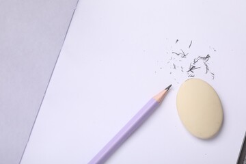 Eraser, pencil and scraps on notebook, flat lay. Space for text