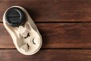Paper coffee cup in cardboard holder on wooden table, top view. Space for text