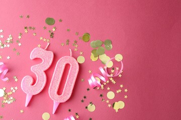 30th birthday. Number shaped candles and confetti on pink background, flat lay. Space for text