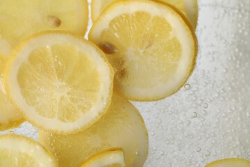 Soda water with lemon slices as background, closeup