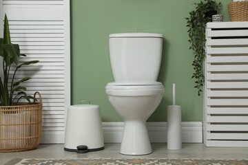 Fototapeta premium Ceramic toilet bowl, brush and necessities in restroom