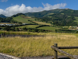 idyllic countryside farmhouses nestled among lush green and yellow fields, framed by a rustic wooden fence