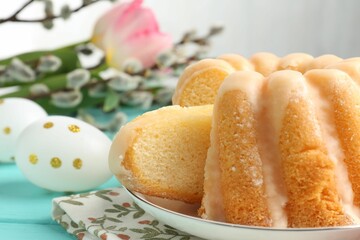 Delicious bundt cake, Easter eggs, willow branches and tulips on table, closeup