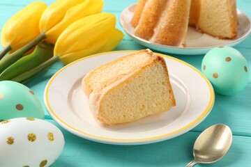 Pieces of delicious bundt cake, Easter eggs and tulips on light blue wooden table, closeup
