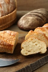 Different types of fresh bread on wooden table, closeup