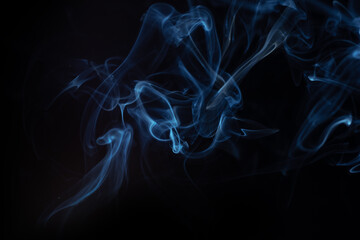 Blue smoke swirls in abstract form on black background. Concept of mystery and creativity. Swirling, writhing smoke to overlay