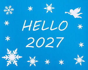 The text HELLO 2027 on a blue background with Christmas snowflakes, a white angel. Happy New Year.