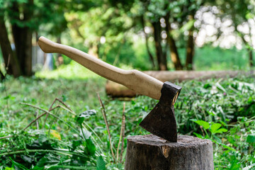 An axe stuck in a tree stump against a forest background